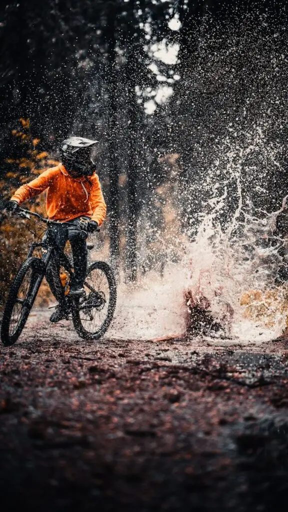 man in orange jacket riding on black mountain bike